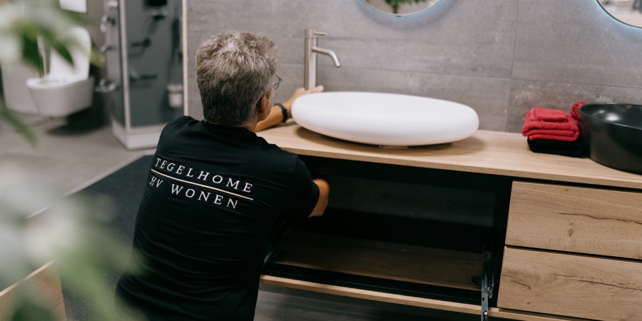 Van eerste idee tot oplevering: wij verzorgen het hele trajec Monteur van tegelhome installeert een badkamermeubel.