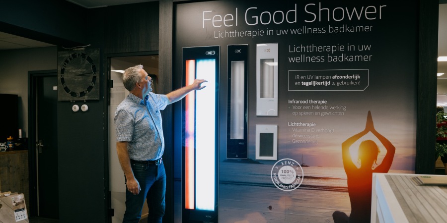 Douchen was nog nooit zo ontspannend Klant bekijkt in showroom van Tegelhome en display over de feel good shower met lichttherapie.