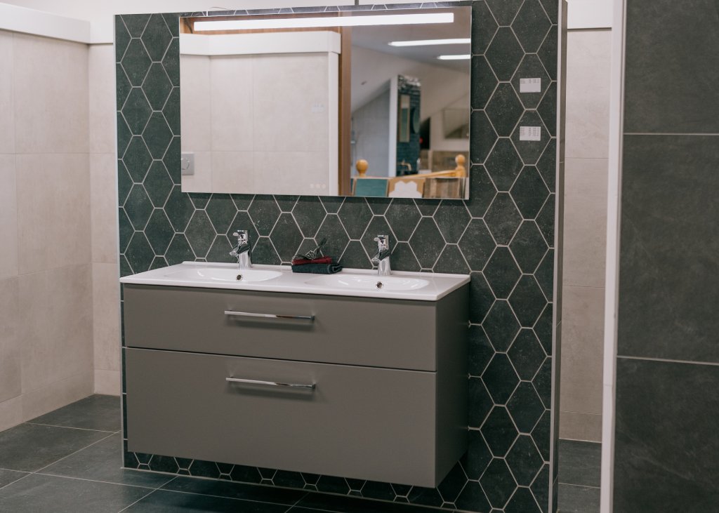 Een donkergroene badkamerwand met een grijs dubbel wasmeubel en een rechthoekige spiegel