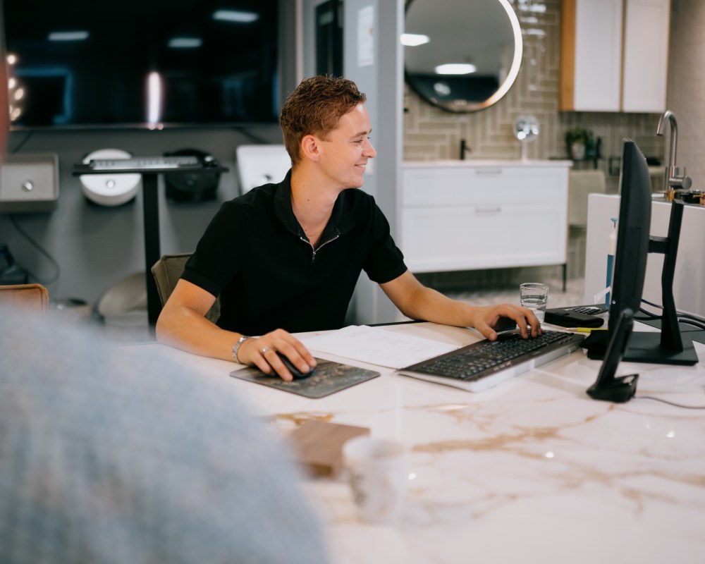 Met een PVC vloer inclusief montage kiest u voor een zorgeloze ervaring Een medewerker van Tegelhome achter een computer