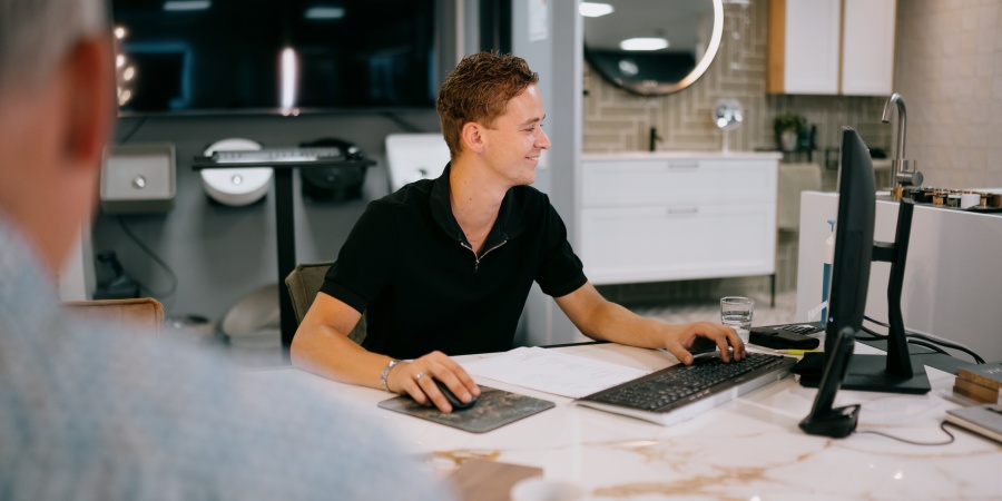 Laat u ontzorgen en kies voor Tegelhome & HV Wonen als uw tegelzetter in Nieuwleusen Medewerker van Tegelhome & HV Wonen achter zijn bureau in gesprek met een klant.