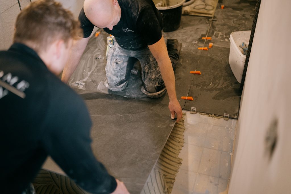 Het team van Tegelhome en HV Wonen zijn vloertegels aan het zetten in een woning.