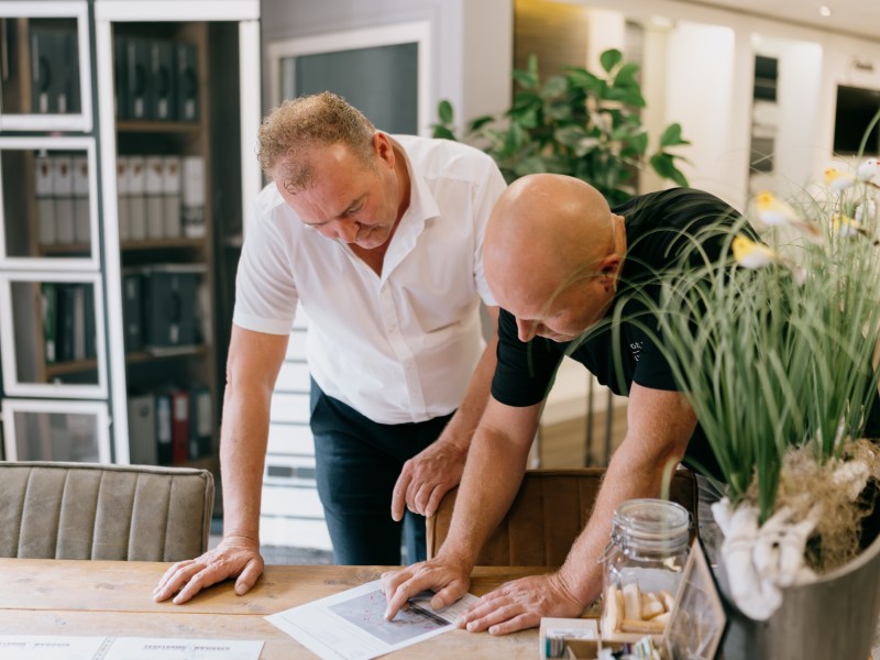 Uw vloerverwarming installeren in Hoogeveen wordt vakkundig uitgevoerd. Medewerkers van Tegelhome buigen zich over een tekening.