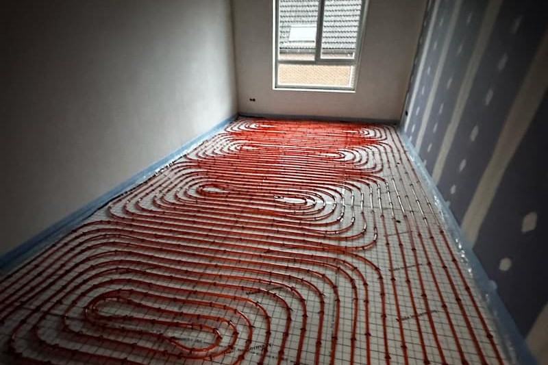 Rode vloerverwarmingsbuizen gelegd in een lege kamer
