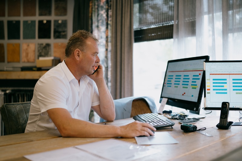 Vloerverwarming in Staphorst laten plaatsen? Neem contact met ons op Een medewerker van Tegelhome bellend achter zijn bureau met computer